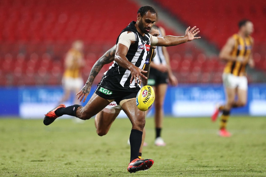 A Collingwood Magpies AFL player kicks the ball against the Hawthorn Hawks.