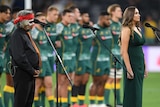 A female singer stands behind a microphone while singing Australia's national anthem before a Wallabies Test.