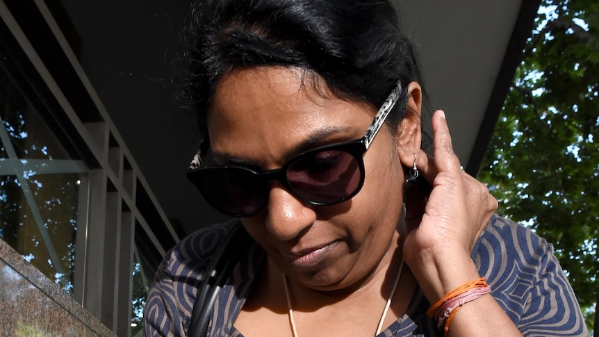 A woman wearing sunglasses walks out of the Melbourne Magistrates' Court.