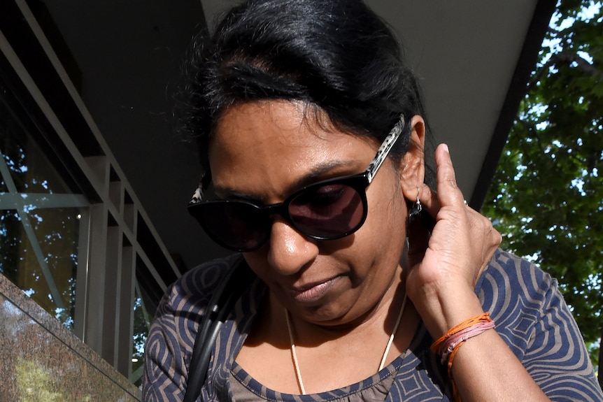 A woman wearing sunglasses walks out of the Melbourne Magistrates' Court.