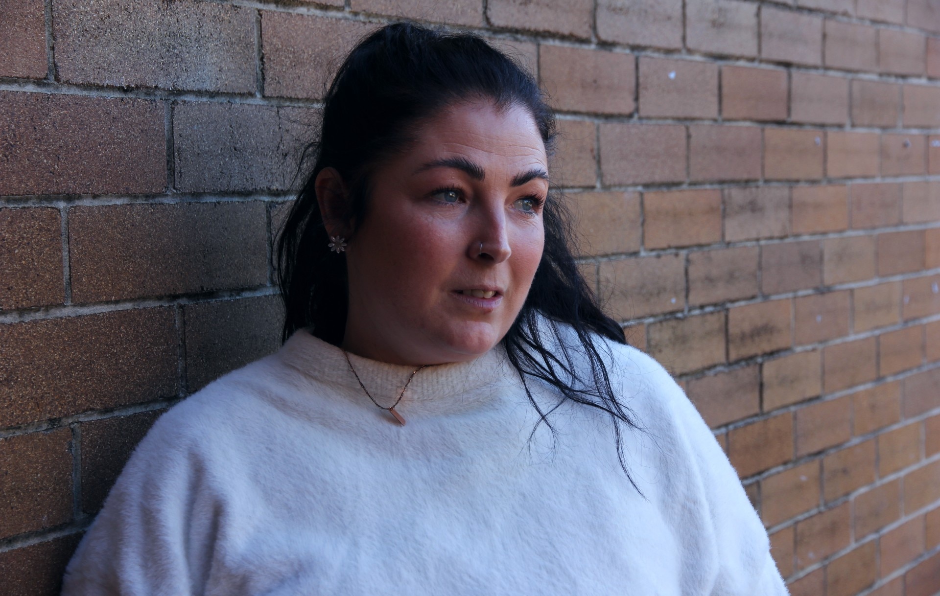 woman with black hair and white jumper