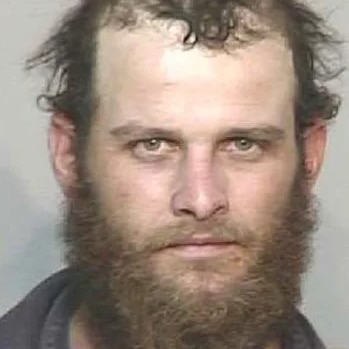Mug shot of Joshua Duke- a white male, with sweaty hair, receding hairline, tradie shirt, bushy beard.