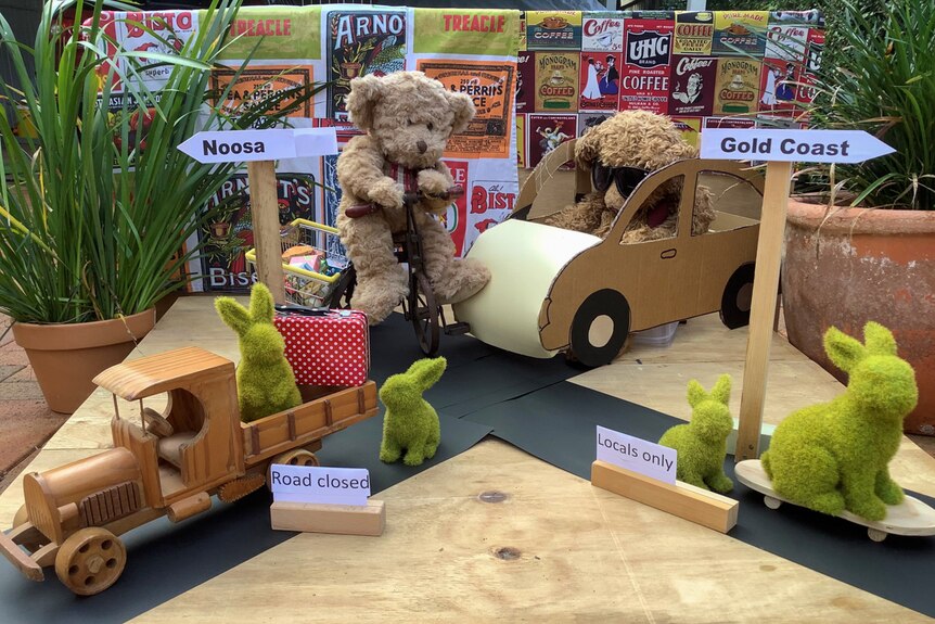 Two teddy bears sit in cardboard cars with green bunnies.