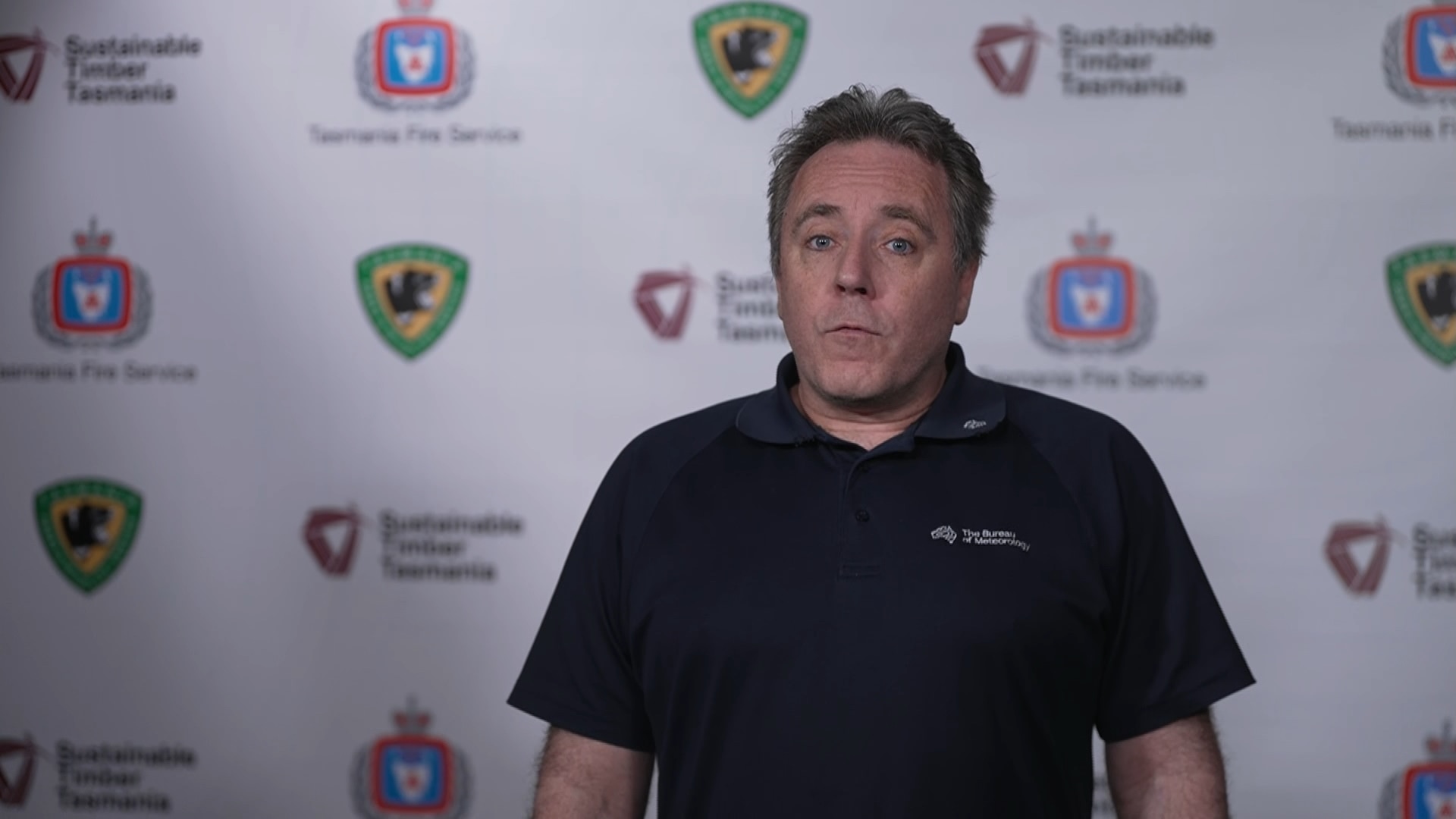 Matthew Thomas, with short, grey hair, in a polo shirt with the Bureau of Meterology logo.