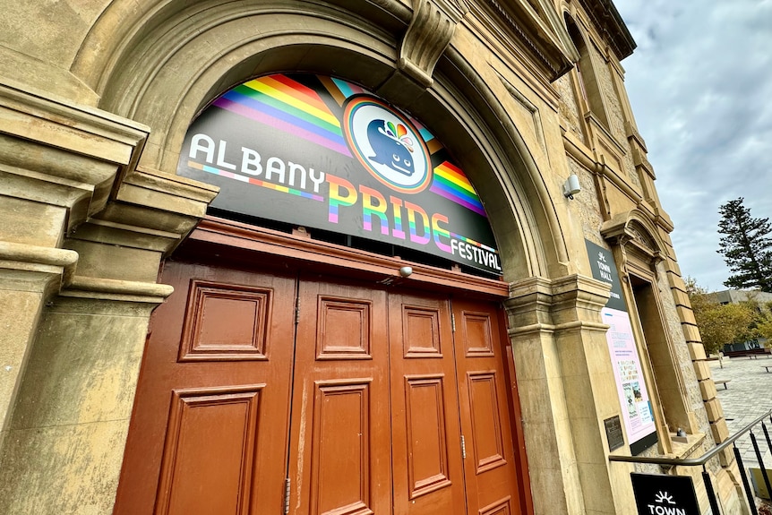 A historic-looking building with a rainbow banner on its facade.