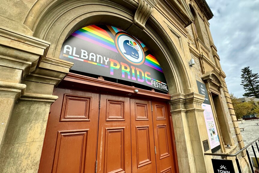 A historic-looking building with a rainbow banner on its facade.