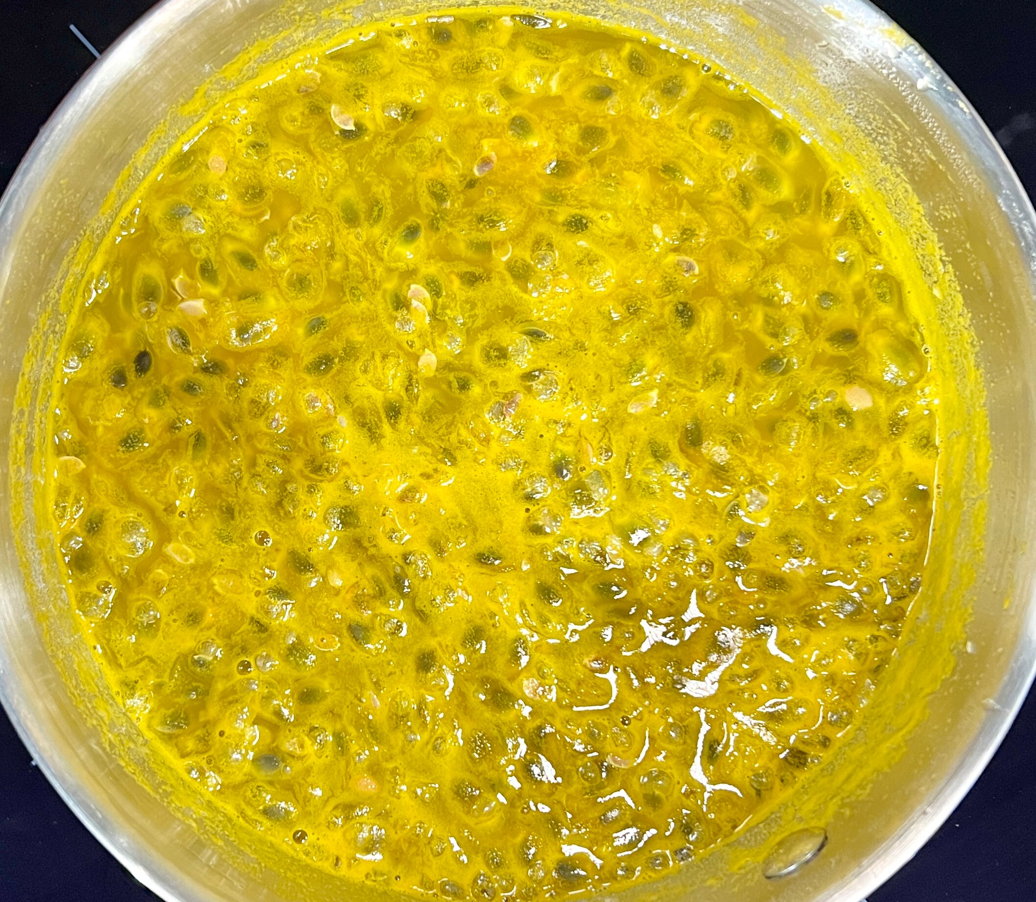 Passionfruit coulis simmering in a pot on a bench top