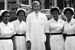 A women in a white doctor's coat poses with four nurses in a black and white photo