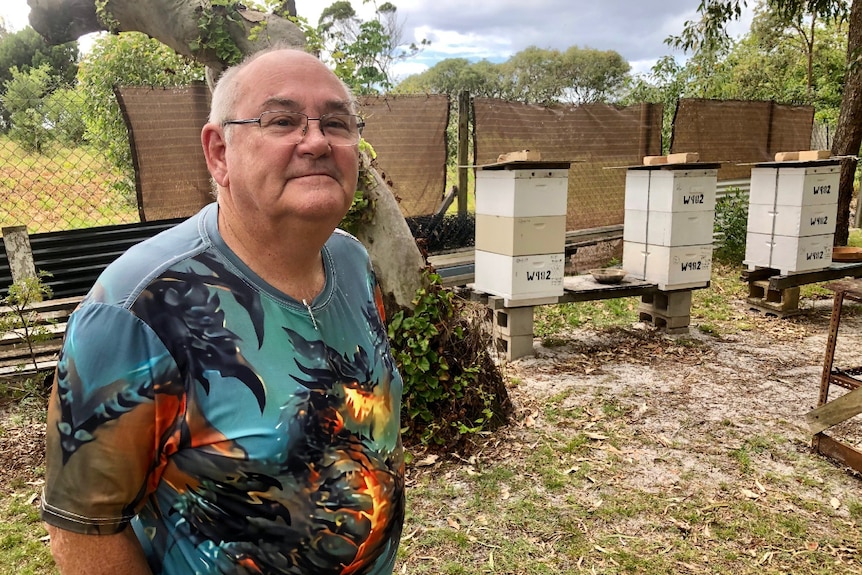 A man standing in front of beehives