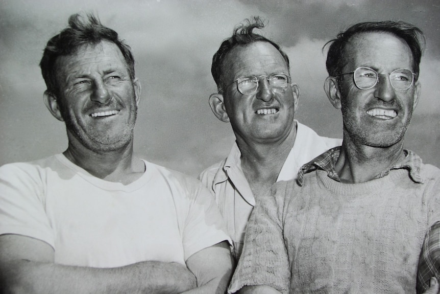 1950s head and shoulders photo of three men two on right with glasses.