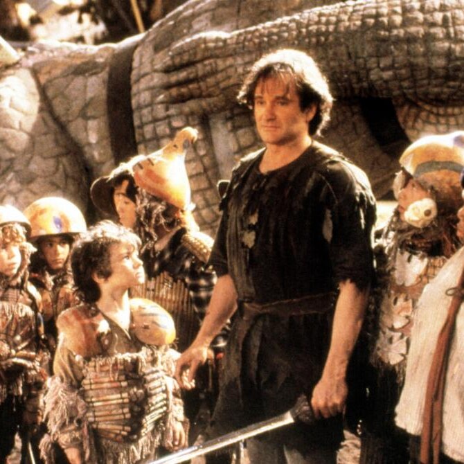 An image of a man with long, messy hair, in bedraggled clothes and holding a sword, surrounded by children ready for battle.