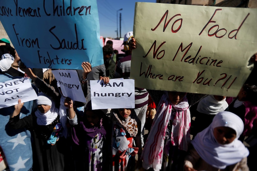 Children holding large signs saying 'No food, no medicine, where are you?!!"