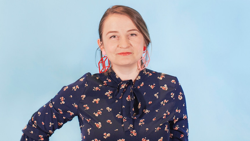 Music programmer Maggie Collins standing in front of a blue background.