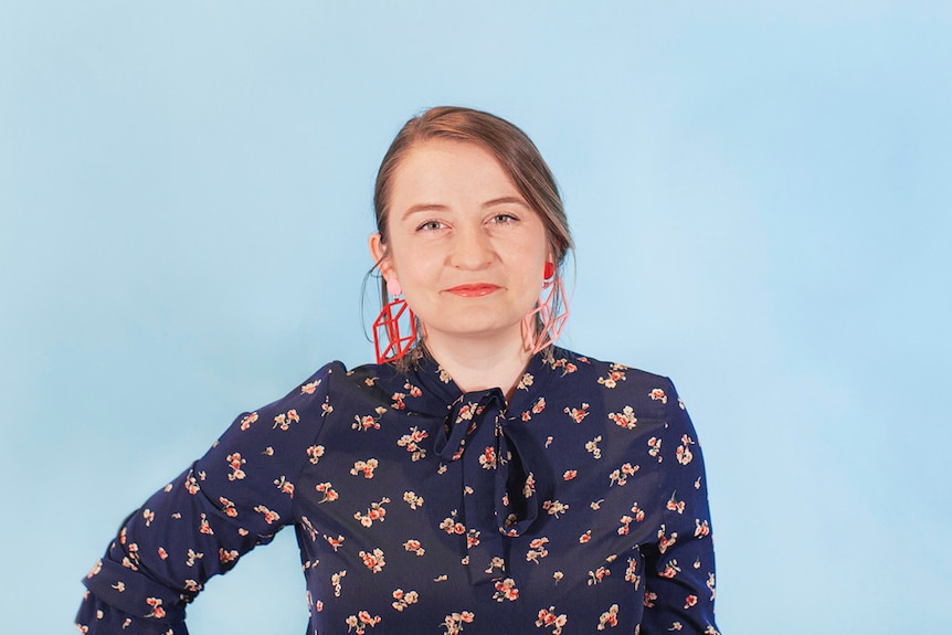 Music programmer Maggie Collins standing in front of a blue background.