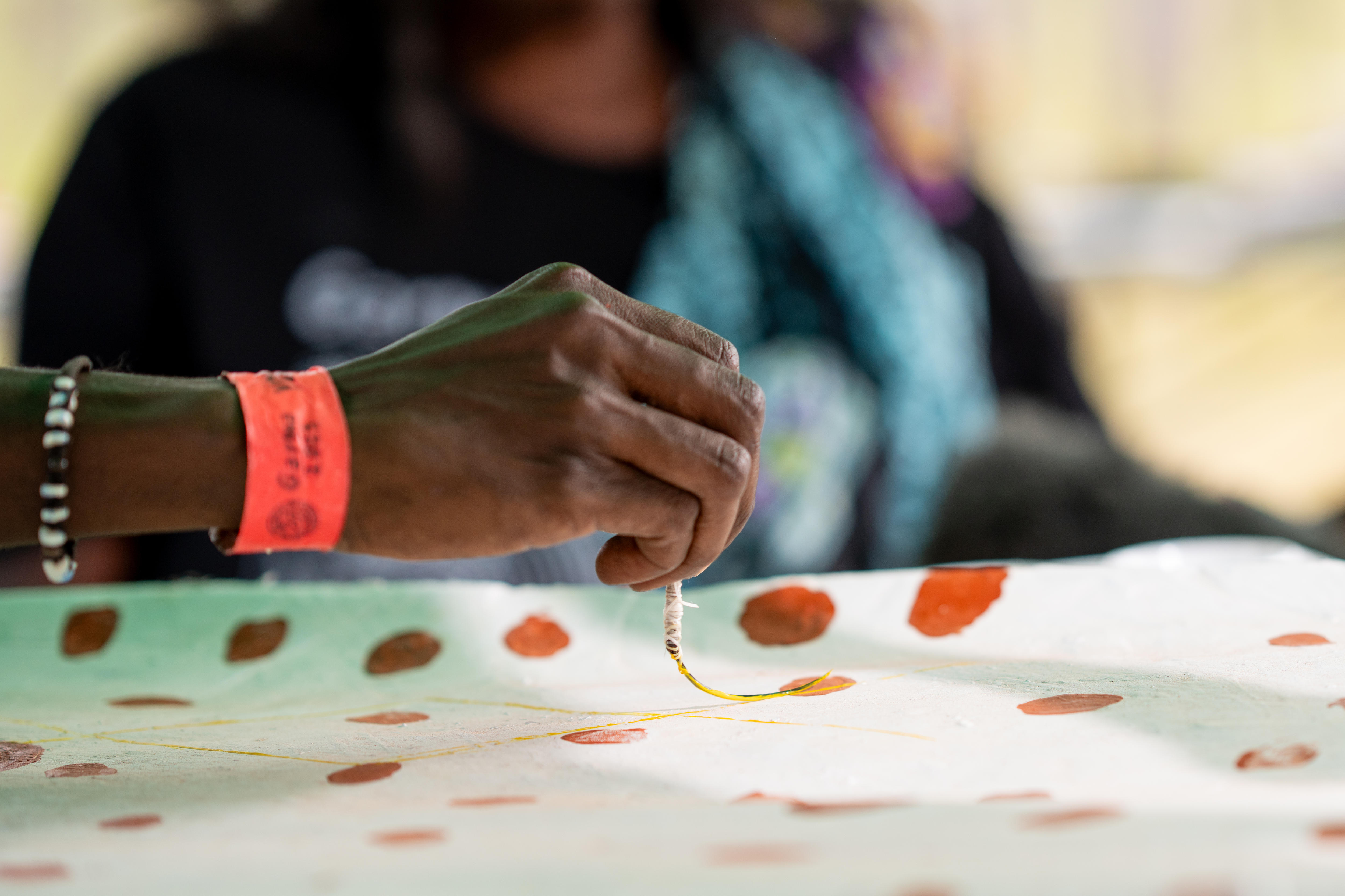 Painting using a hair snipped from Siena's head. They are painting using the brush. 