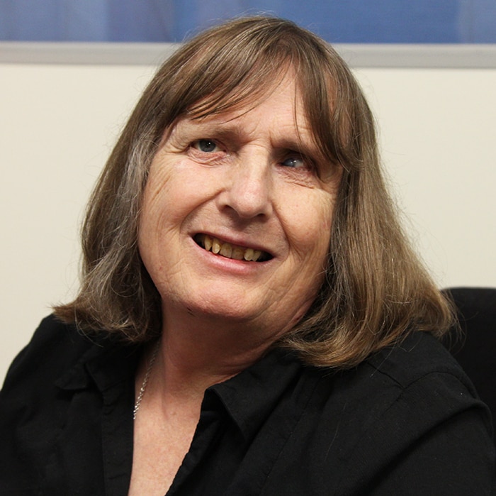 A woman with shoulder-length light brown hair smiles at the camera.