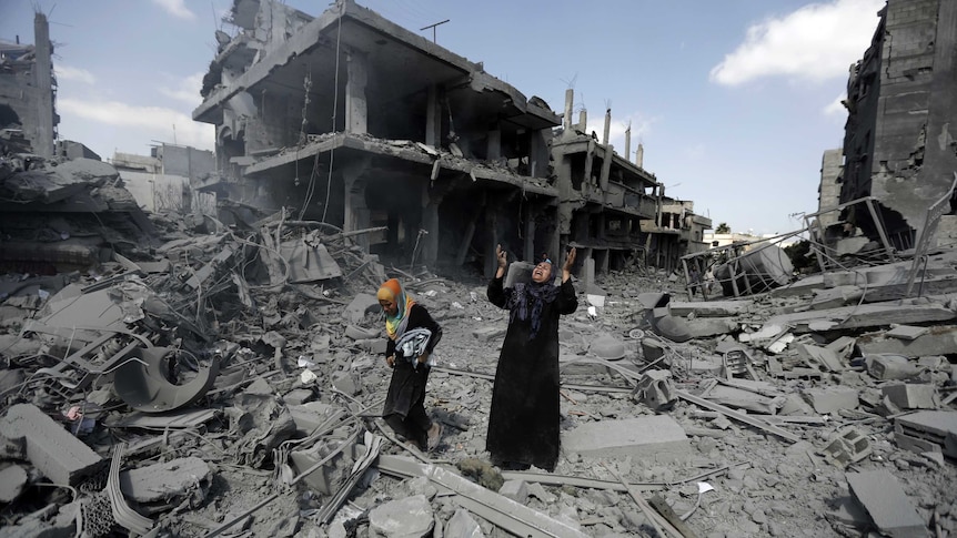 Palestinian woman pauses amid destroyed Gaza buildings