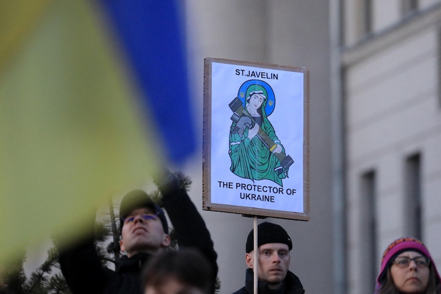A protester holds a sign reading "St Javelin- the protector of the Ukraine". 
