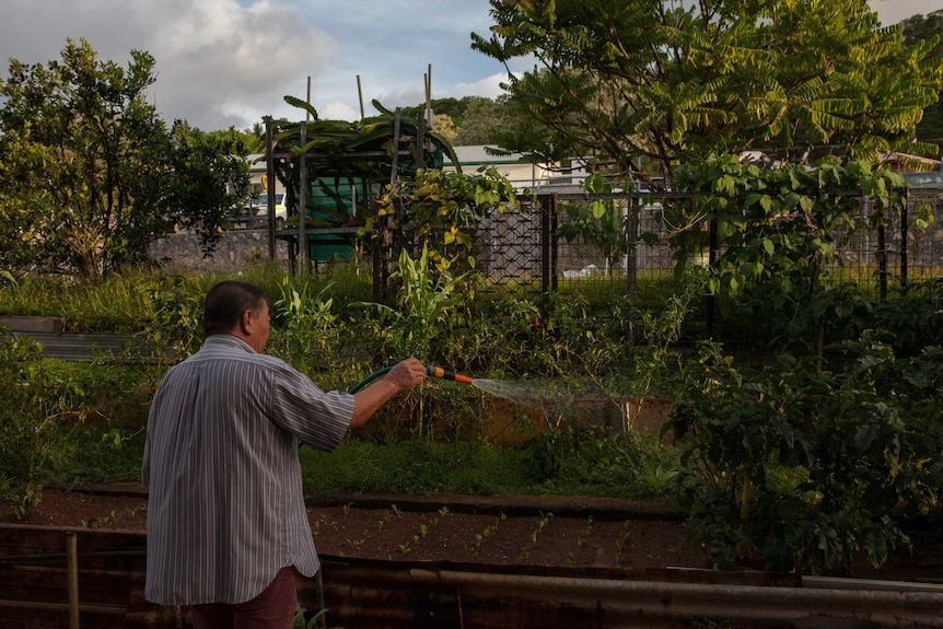 A man waters his plants outside his Christmas Island home.