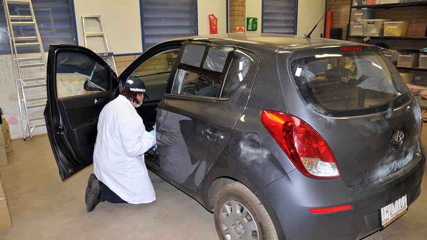 A police officer examines the grey Hyundai i20 car that was driven by the alleged offender