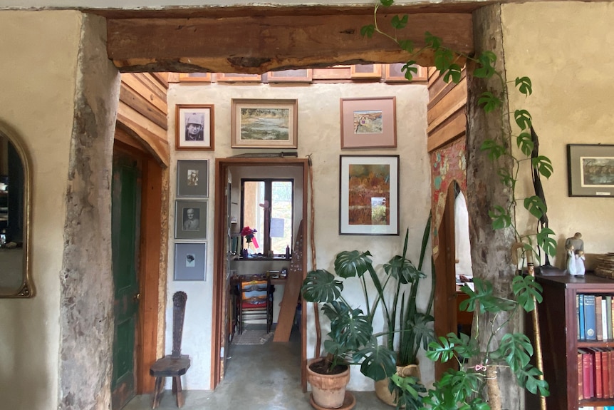 A picture of the middle wall of the house, which is mud brick, bordered by wood from trees 