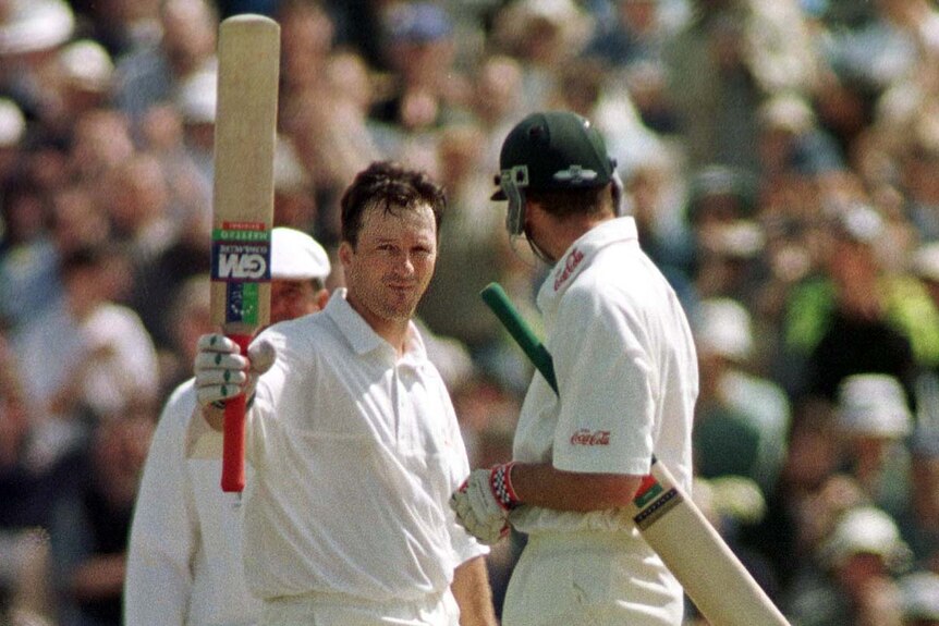 Steve Waugh raises his bat, as his partner looks on, after scoring a second century in the 1997 Ashes Test at Old Trafford.
