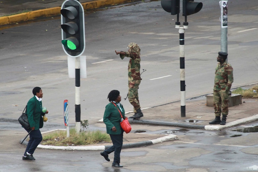 Armed soldiers stand on the road leading to President Robert Mugabe's office, as school children walk past.