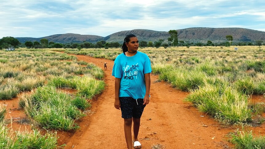 A young woman stands in bushland smiling