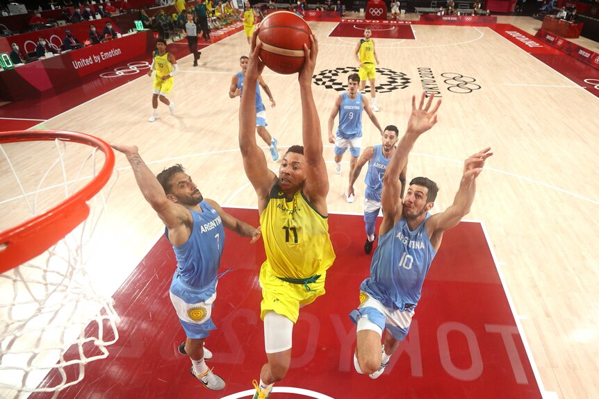 Australia's Dante Exum rises above the rim to dunk the basketball over two Argentina players.
