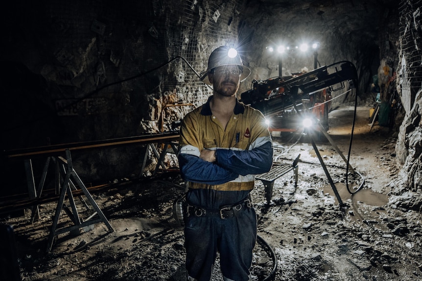 A mine worker in an underground mine wearing high-vis workwear and a hard hat.