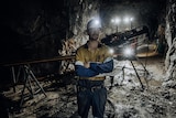 A mine worker in an underground mine wearing high-vis workwear and a hard hat.