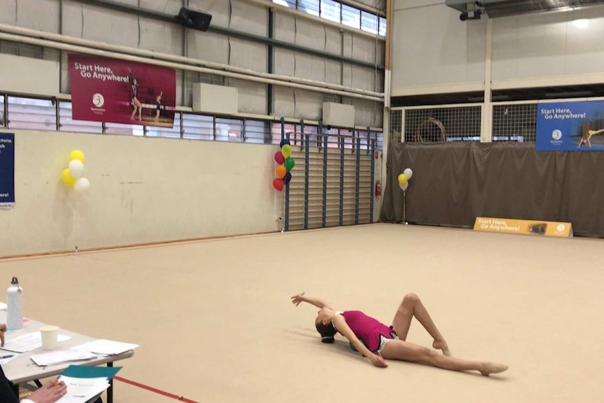 A gymnast doing a floor routine with judges marking her