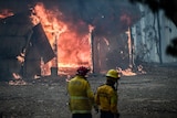 firefighters stand in front of burning shed