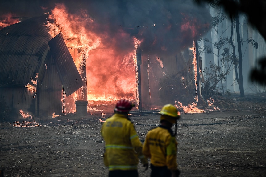 fire fighters stand in front of burning shed