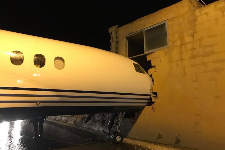 Plane's nose pokes into an office building.