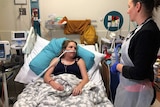 Dr Lucy Burr standing by the bed of patient Tammie Allard, with tubes in her nose.