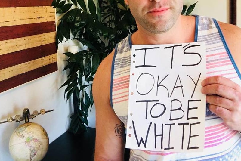 Man holding 'It's okay to be white' sign