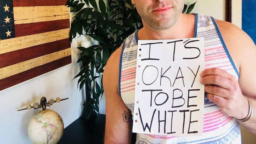 Man holding 'It's okay to be white' sign