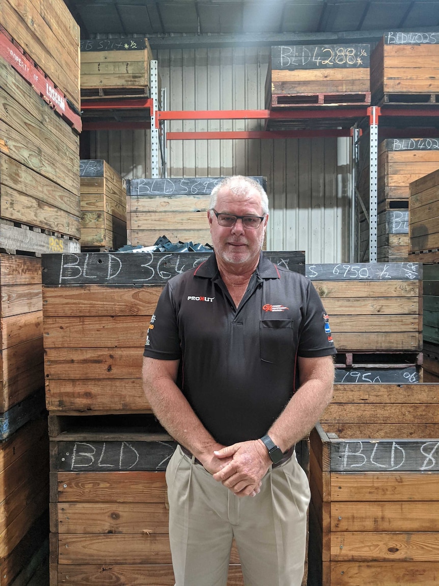 A man with glasses and grey hair stands in a warehouse where his family business in run from.