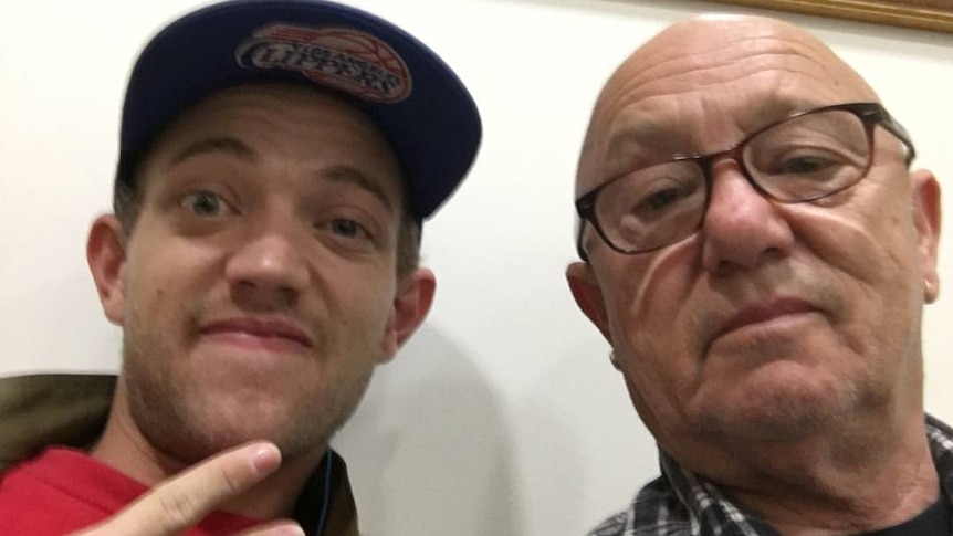 A young man in a cap with an older man in glasses