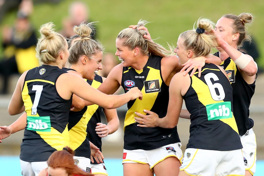 AFLW players celebrate after kicking a goal during a match