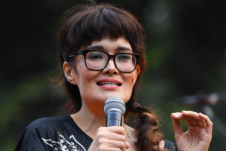 A woman wearing glasses talks into a microphone