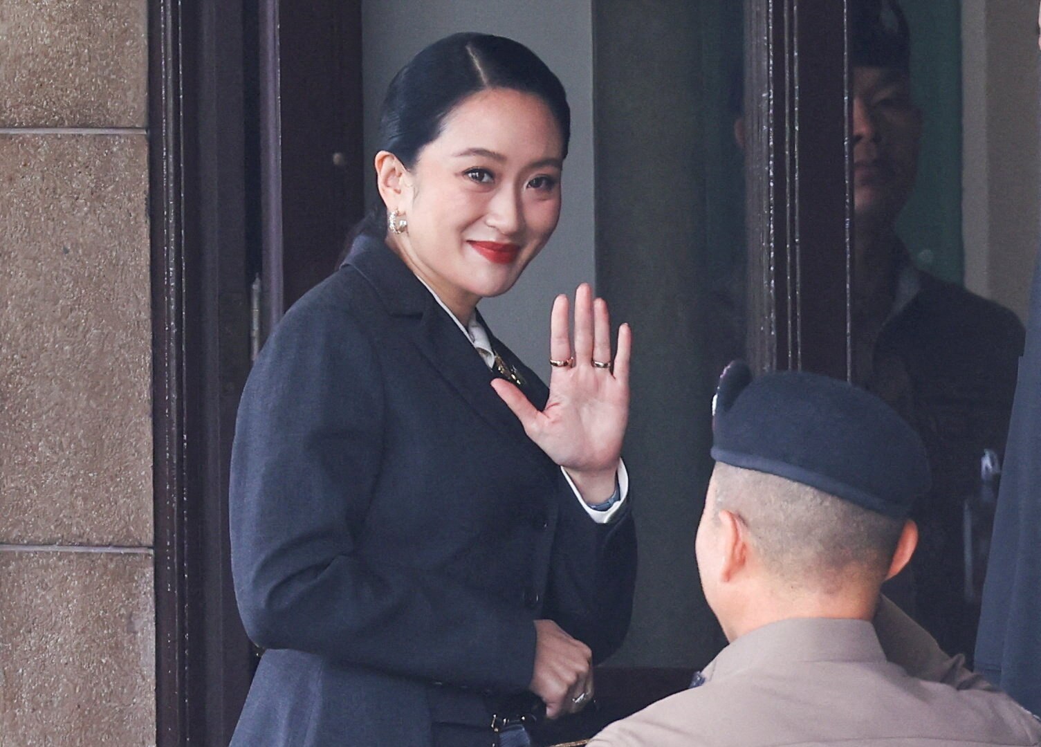 A female with dark hair smiles and waves at the camera