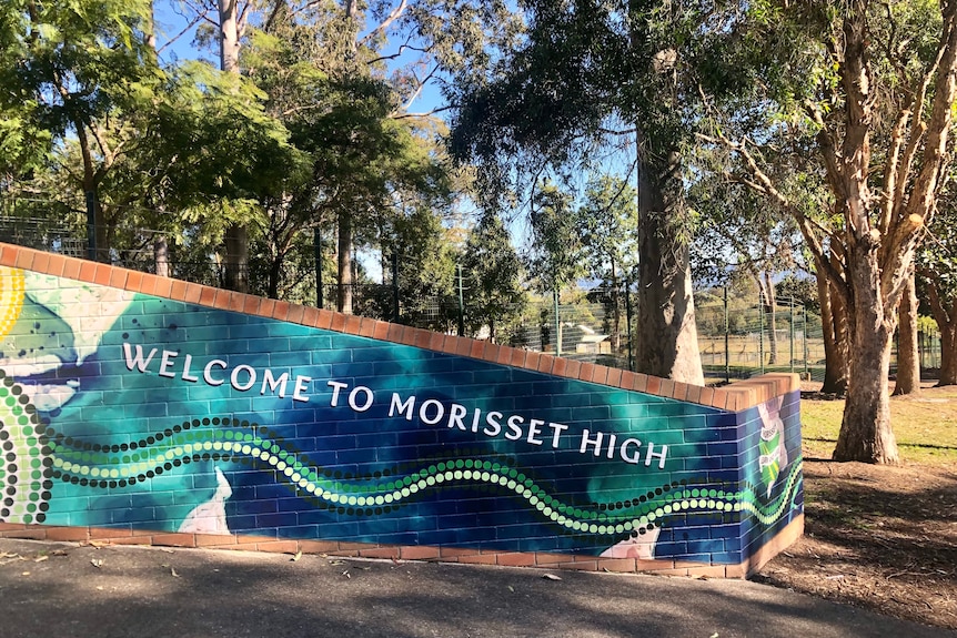 The brick mosaic entrance of a school with trees behind