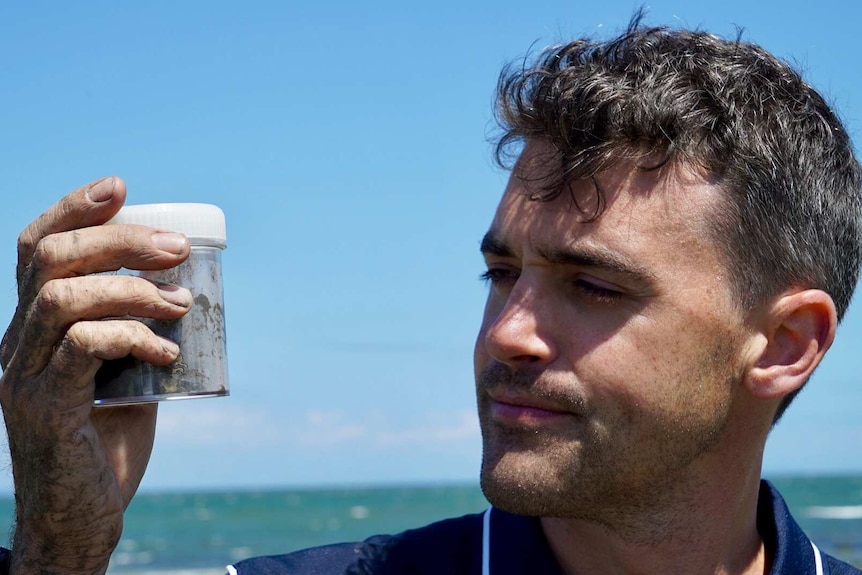 Man holding sample of muddy water