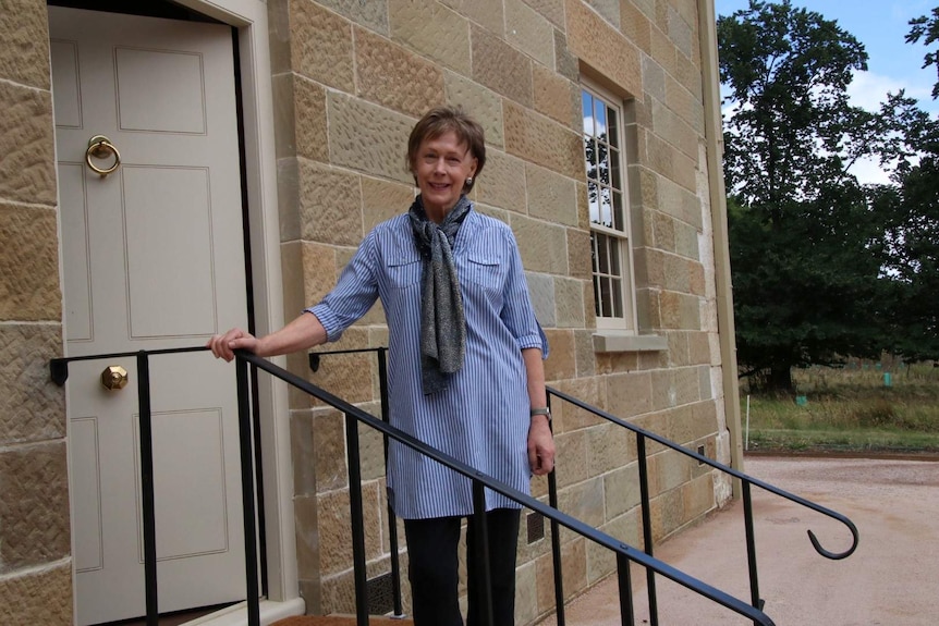 A woman stands outside a sandstone building