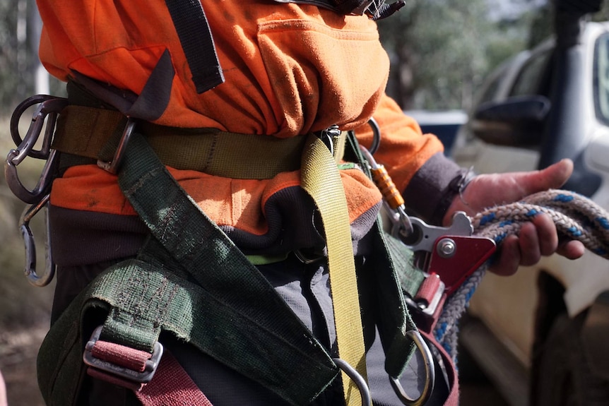 A man tightens a safety harness around his waist.