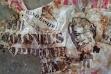 A torn, branded plastic bag is spread out on a concrete floor.