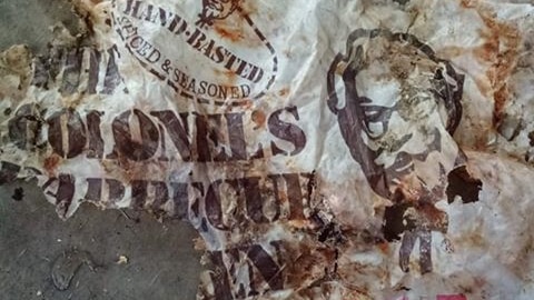 A torn, branded plastic bag is spread out on a concrete floor.