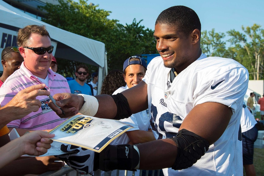 Michael Sam, the first publicly gay player drated into the NFL, signs autographs.
